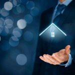 Hand holding a glowing digital house icon, symbolizing smart home tech.