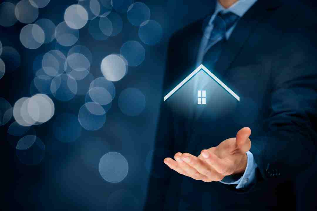 Hand holding a glowing digital house icon, symbolizing smart home tech.